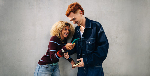 Friends laughing together while sharing a phone