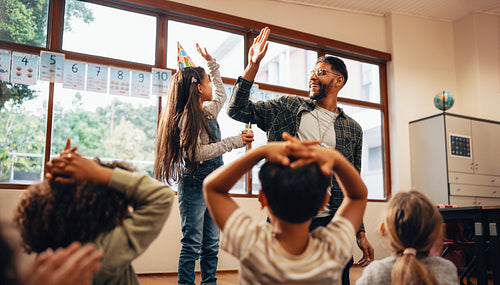Teacher giving a high five to a student with a birthday. Celebration in an elementary school class