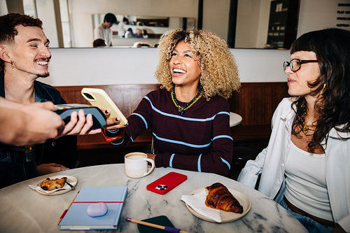 Friends in cafe making a mobile payment