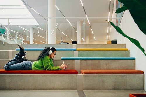 Creative postgraduate student using tablet with headphones in library
