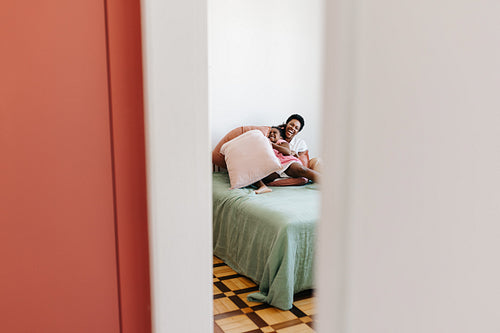 Woman and her daughter laughing together after a fun pillow fight