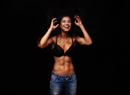 Cheerful young woman in bra and jeans