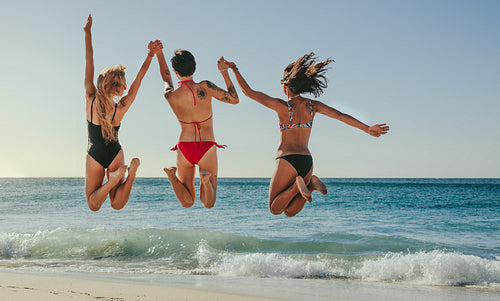 Women jumping in air and enjoying at the beach
