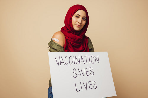 Muslim woman with "Vaccination saves lives" banner