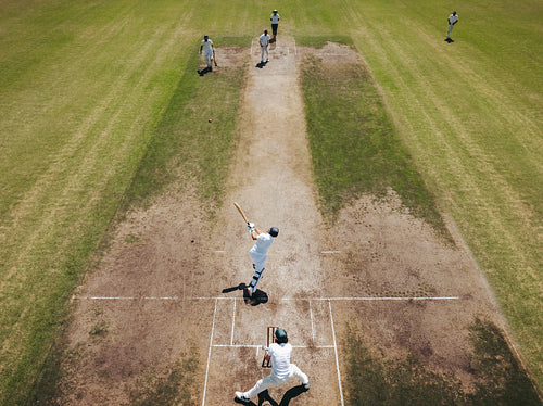 Cricketer taking a powerful shot on the pitch during a match