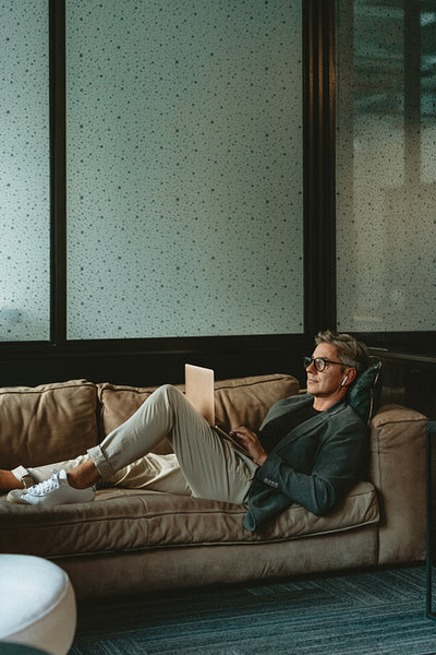 Businessman lying on the sofa working on laptop