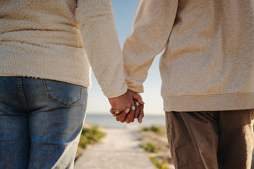 Romantic senior couple holding hands at the beach