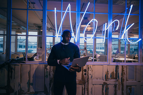 African young man standing in office using laptop