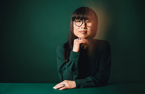Thoughtful woman in glasses holds a professional portrait pose in the studio