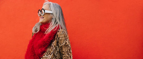Happy grey-haired woman smiling cheerfully against a red background