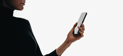 An anonymous woman holding a smartphone while browsing in a minimal setting