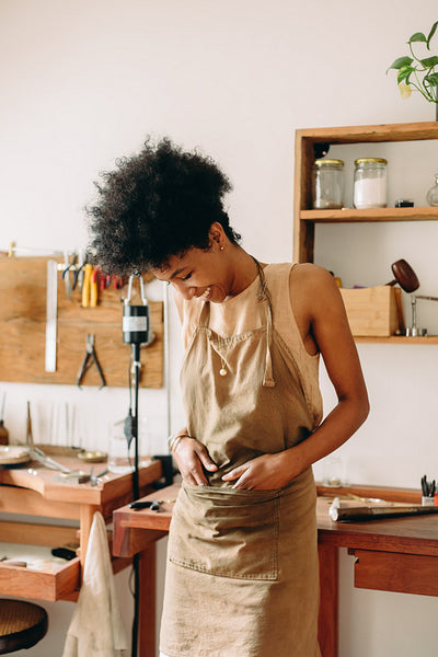Cheerful jewelry artist standing at workshop