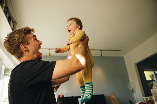 Man playing with his baby boy at home