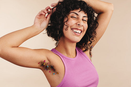 Happy young woman showing off her decorated underarm hair