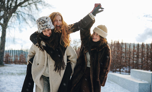 Friends watch women enjoy a piggyback ride in snow