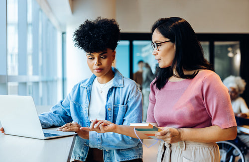 Two colleagues work together at laptop