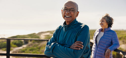 Cheerful elderly man smiling at the camera on a foot bridge