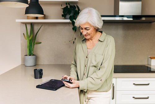 Mature woman using a smartphone indoors at home