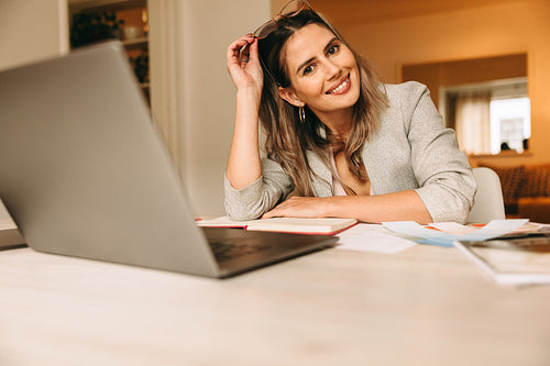 Cheerful interior designer sitting at her desk in her home offic