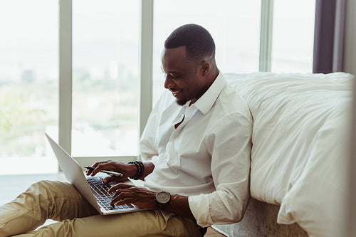 Smiling businessman working from his bedroom at home