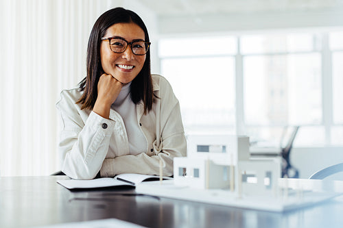 Female architect sitting with a 3d house model in an office