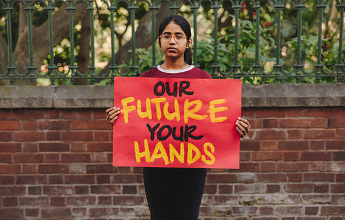 Young girl holding a climate change poster outdoors