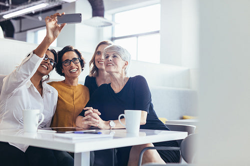 Businesswomen taking selfie at office cafeteria