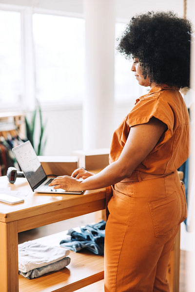 Black businesswoman using a laptop in her clothing store