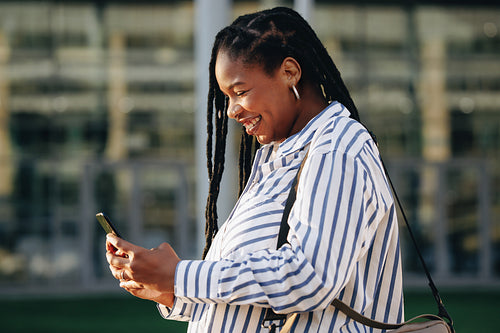 Smiling business woman using a smartphone while commuting in the city