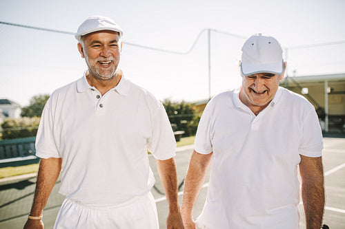 Senior men walking on a tennis court during a game of tennis