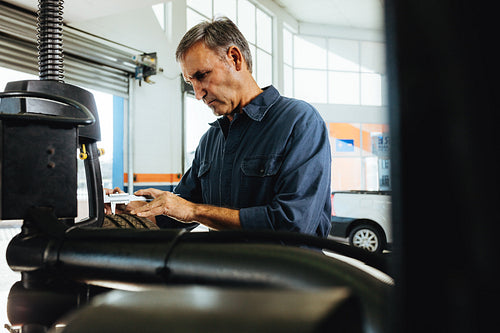Technician working in automobile tyre mounted on machine