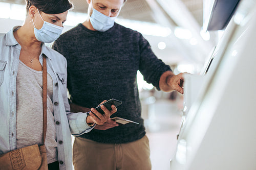 Couple at airport self-service check-in machine