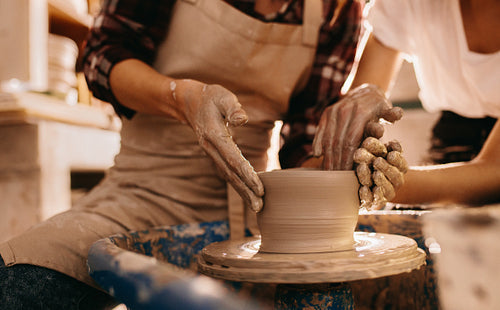 Two women at a pottery workshop making clay pots