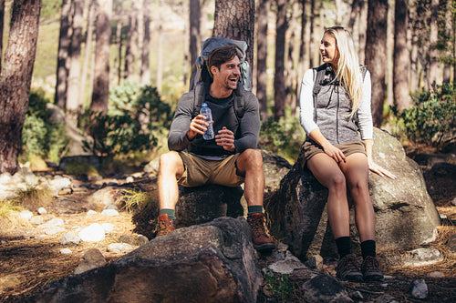 Hiking couple relaxing sitting on rocks during trekking