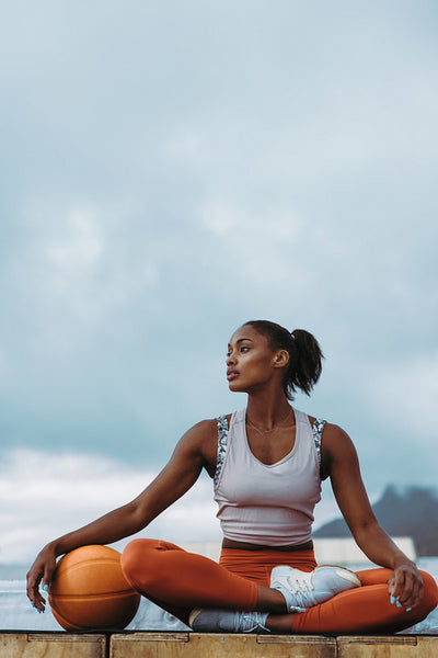 Sportswoman with basketball relaxing on rooftop