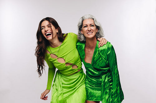 Two women of different ages laugh and hug in studio