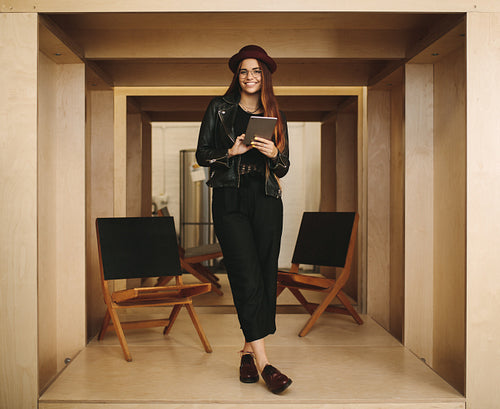 Portrait of a smiling woman entrepreneur standing in office holding digital tablet