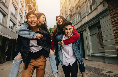 Friends piggybacking outdoors on city street