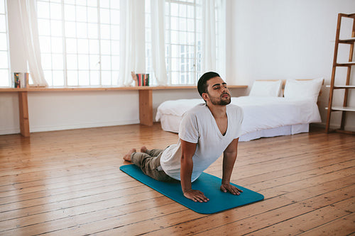 Healthy young man practicing yoga at home