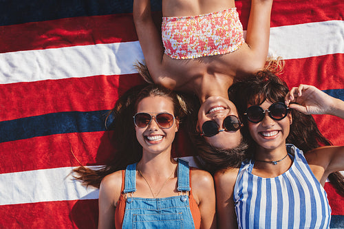 Female friends lying on striped towel on the sea shore