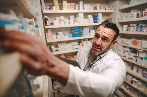 Pharmacy store owner checking stock on shelves