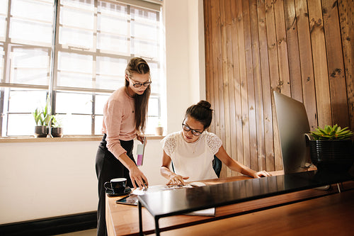 Two business women reading documents on desk