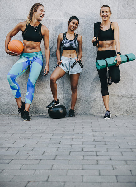 Three women in training wear standing outdoors after workout
