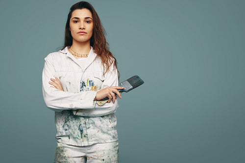 Young painter standing in a studio with paintbrushes in her hand