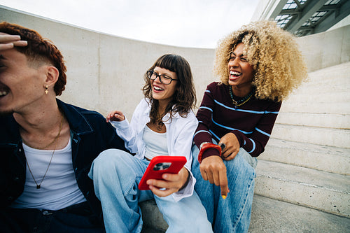 Friends laughing together on concrete steps, diverse group