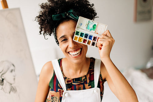 Playful female painter covering her eye with a palette
