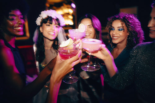 Group of friends celebrating a fun night out with colorful cocktails