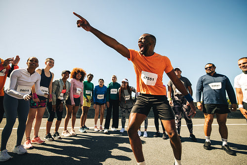 Energetic running coach hyping up diverse group before a race