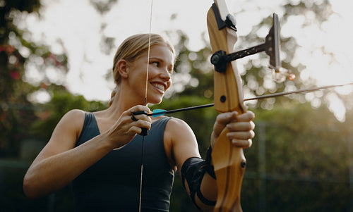 Smiling woman practicing archery outdoors