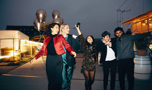 Group of friends celebrating outdoors in the evening holding balloons